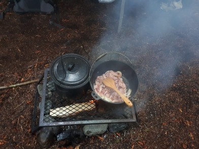 Wir kochen auf einem Grillrost, der ueber einem Holzfeuer positioniert wird.